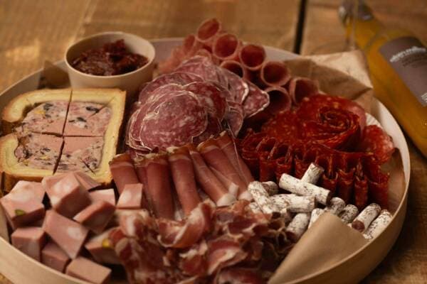 Gros plan sur un plateau de charcuterie : pâté en croûte, saucisson, coppa et jambon roulé