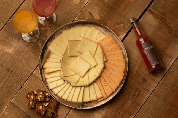 Plateau de raclette vu de dessus : tranches de fromage nature et fumé disposées en rosace