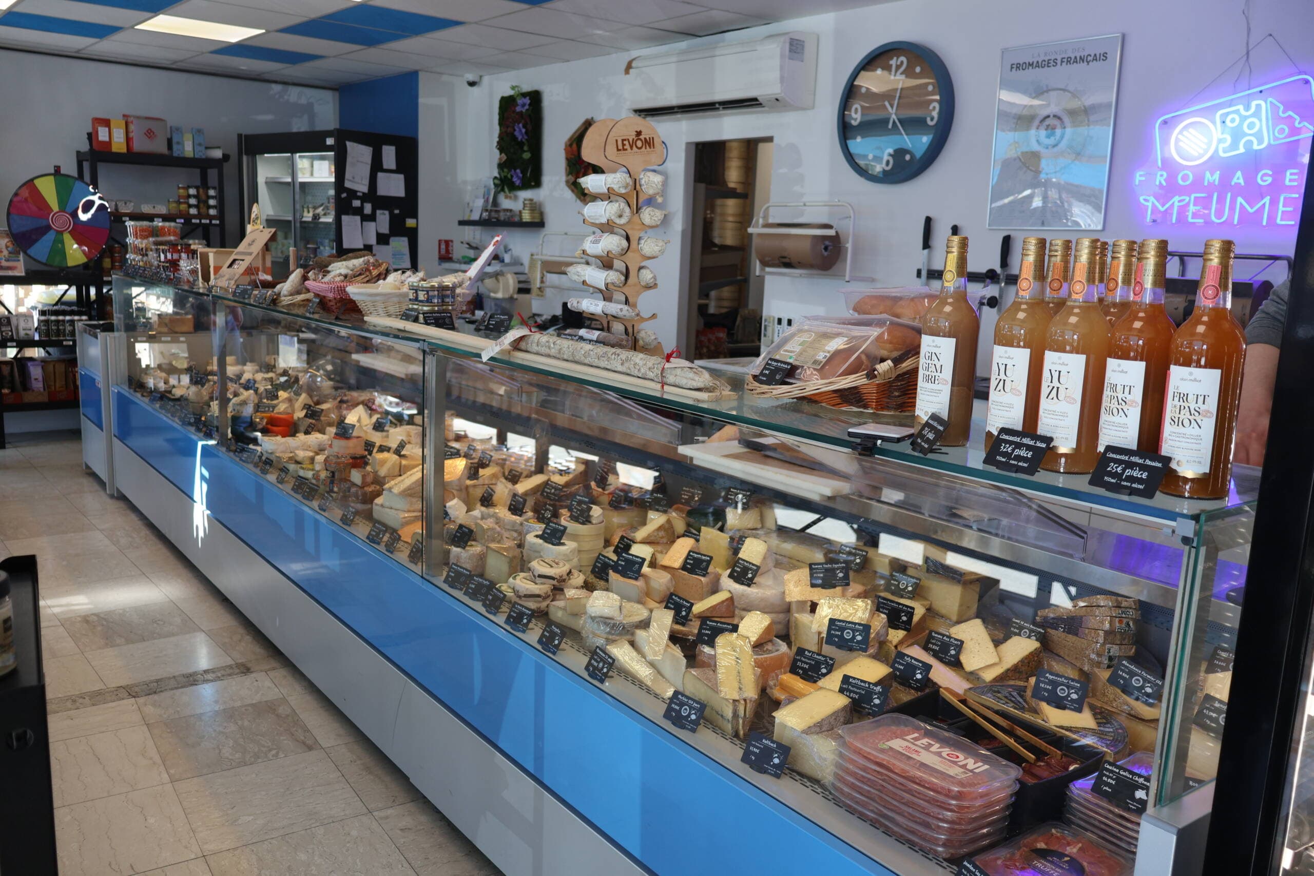 Le comptoir réfrigéré de la Fromagerie Meumeu, ses fromages à la coupe et ses jus artisanaux